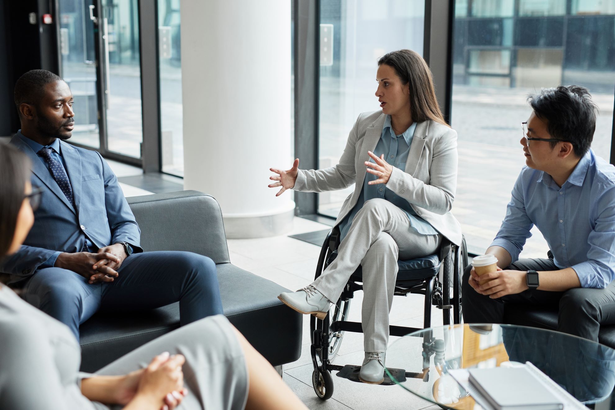 Businesswoman in a wheelchair communicating with a group of colleagues.