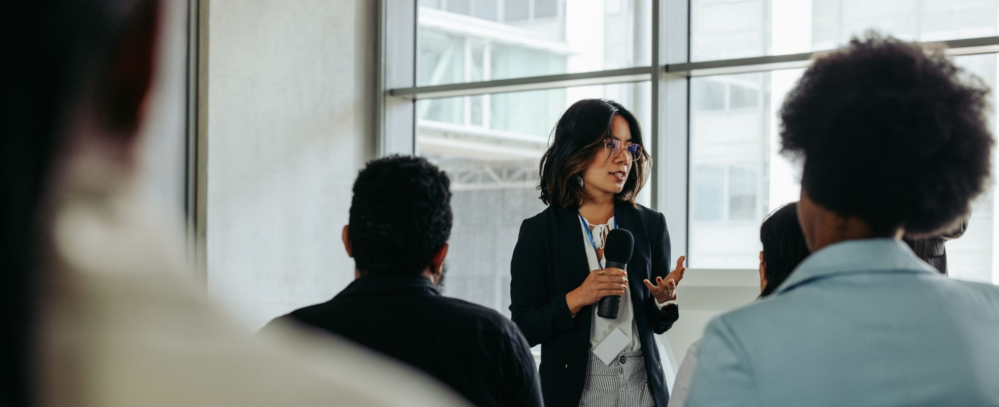 A woman speaking at an event and looking out at a room full of people